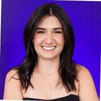 Foto de rosto de Iara sorrindo, com cabelos escuros em um fundo roxo