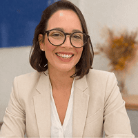 Foto de rosto de Rafaely sorrindo, usando óculos e blazer claro